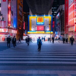 A group of people walking across a street at night